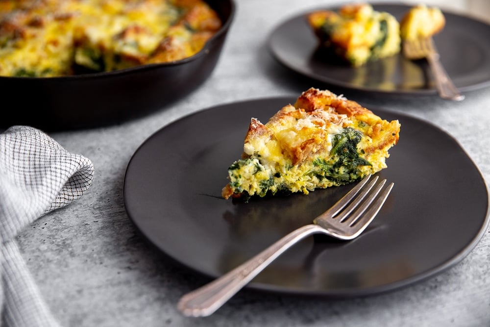 Slice of vegetarian breakfast strata on a plate with a fork
