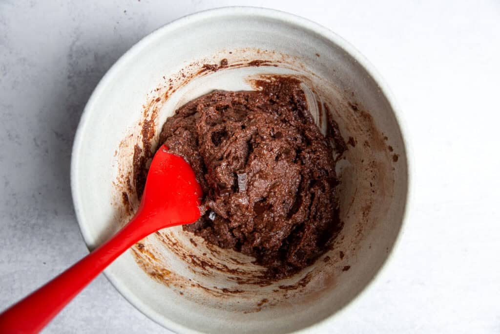 Mixing gluten free chocolate cookie dough with chopped chocolate in a bowl