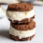 Stack of gluten free ice cream sandwiches with chocolate cookies and vanilla coconut ice cream on a white surface