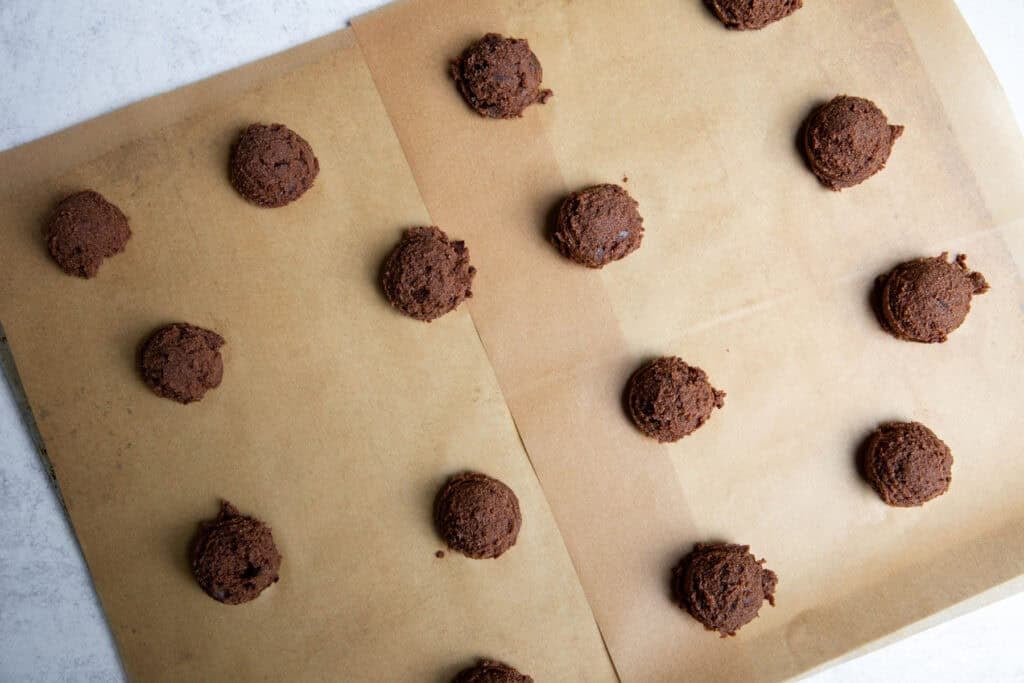 Cookie dough mounds on parchment-lined baking sheet before baking