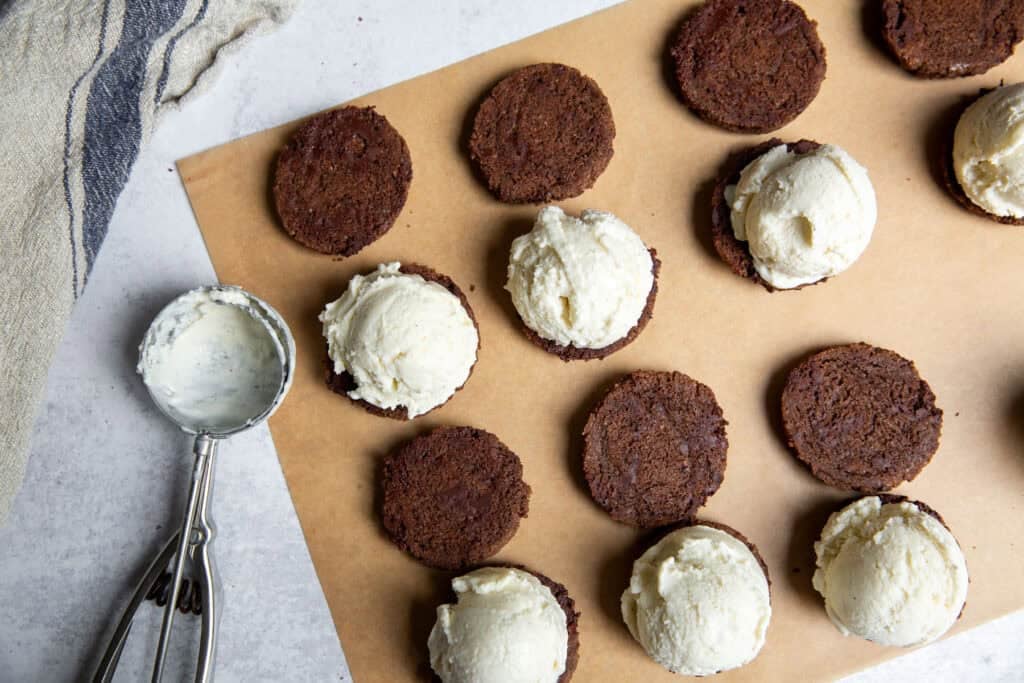 Assembling ice cream sandwiches with scoops of coconut ice cream between cookies