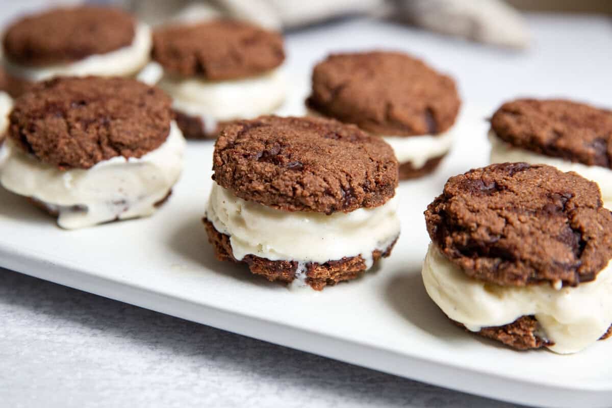 gluten free ice cream sandwiches on parchment paper with visible layers of creamy vanilla filling