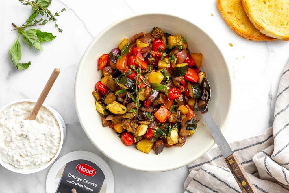 Ratatouille in serving bowl with toasted bread and cottage cheese alongside for serving