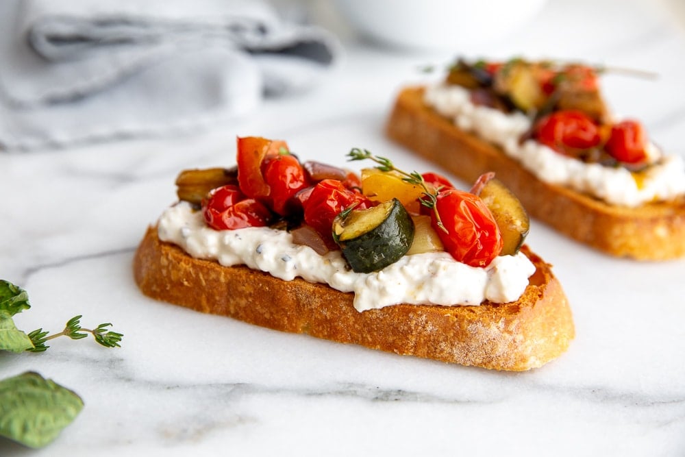 Two slices of toasted bread topped with cottage cheese and ratatouille
