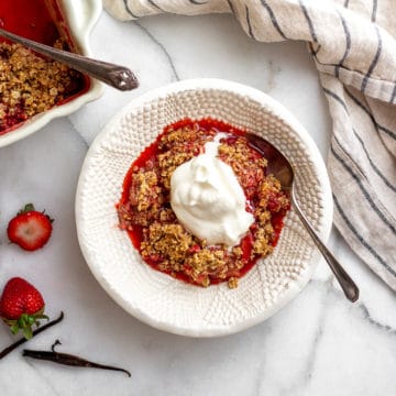 Gluten free strawberry crisp in bowl with whipped cream on top