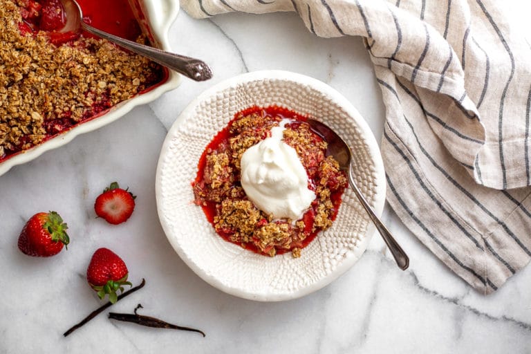 Gluten free strawberry crisp in bowl with whipped cream on top