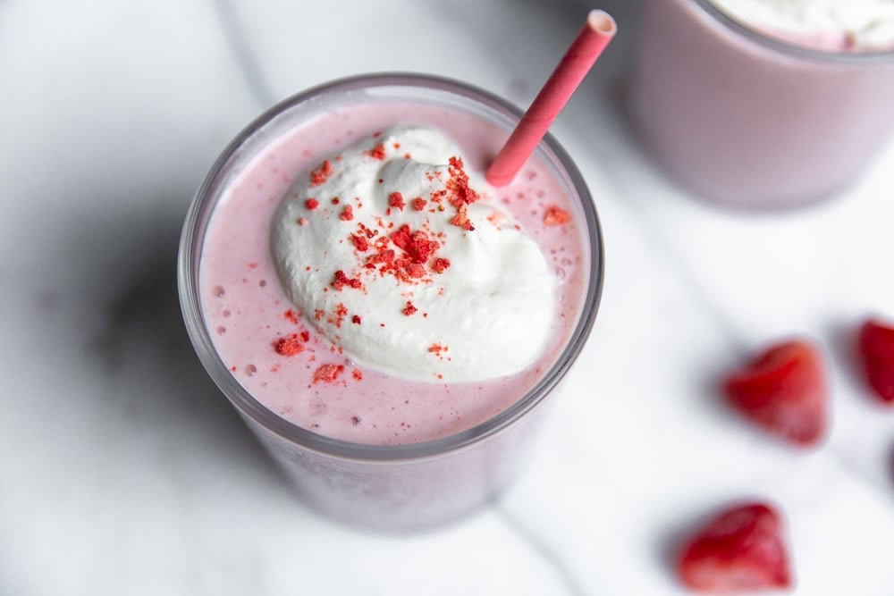 Close-up of whipped cream and crushed freeze-dried strawberries on top of cottage cheese smoothie