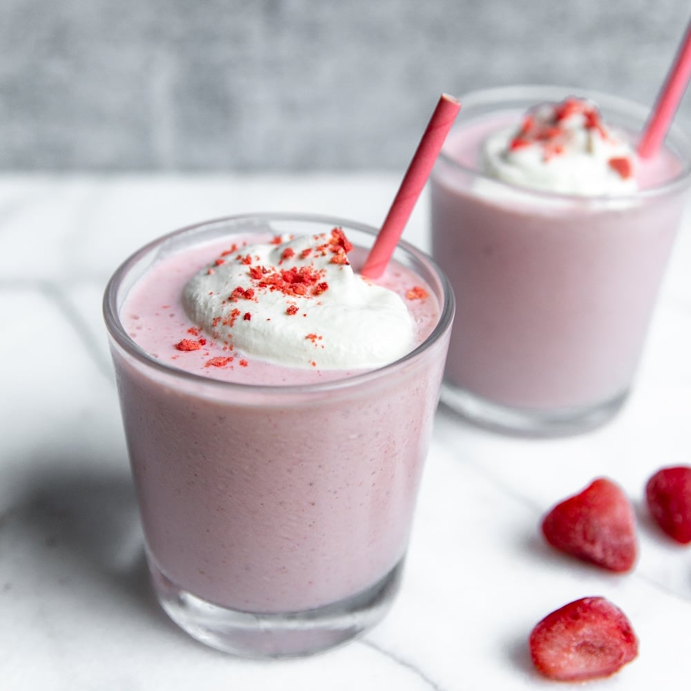 Close-up side view of a strawberry cottage cheese smoothie in a glass with a straw