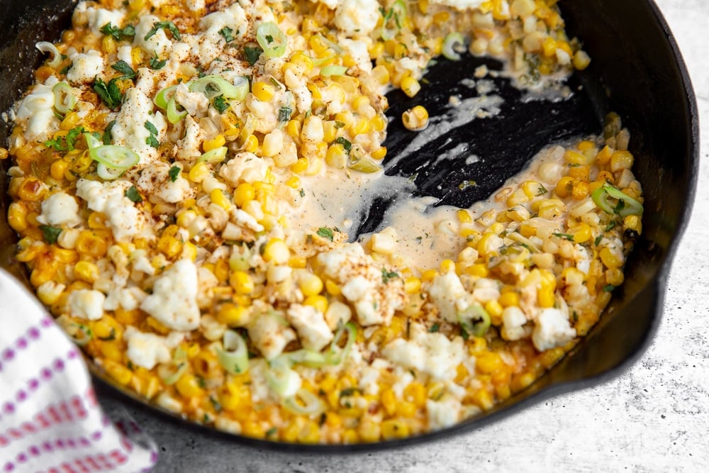 Half eaten elote dip in cast iron skillet