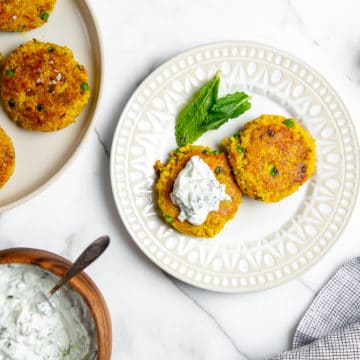 Millet cakes on plate, topped with cucumber mint raita