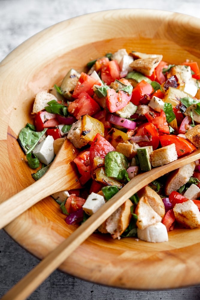 Close-up side view of panzanella salad in a large wooden salad bowl. 