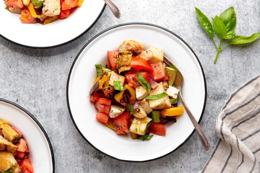 Grilled panzanella salad in serving bowls on table.