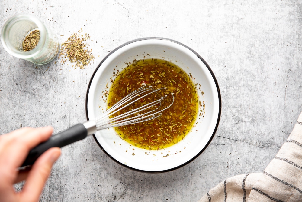Overhead shot of hand whisking together the panzanella salad dressing