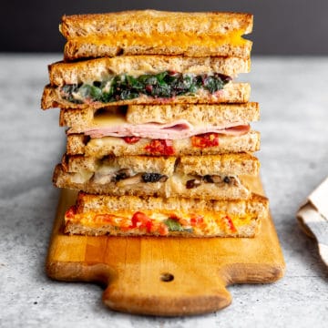 Oven grilled cheese sandwiches stacked on a serving board.