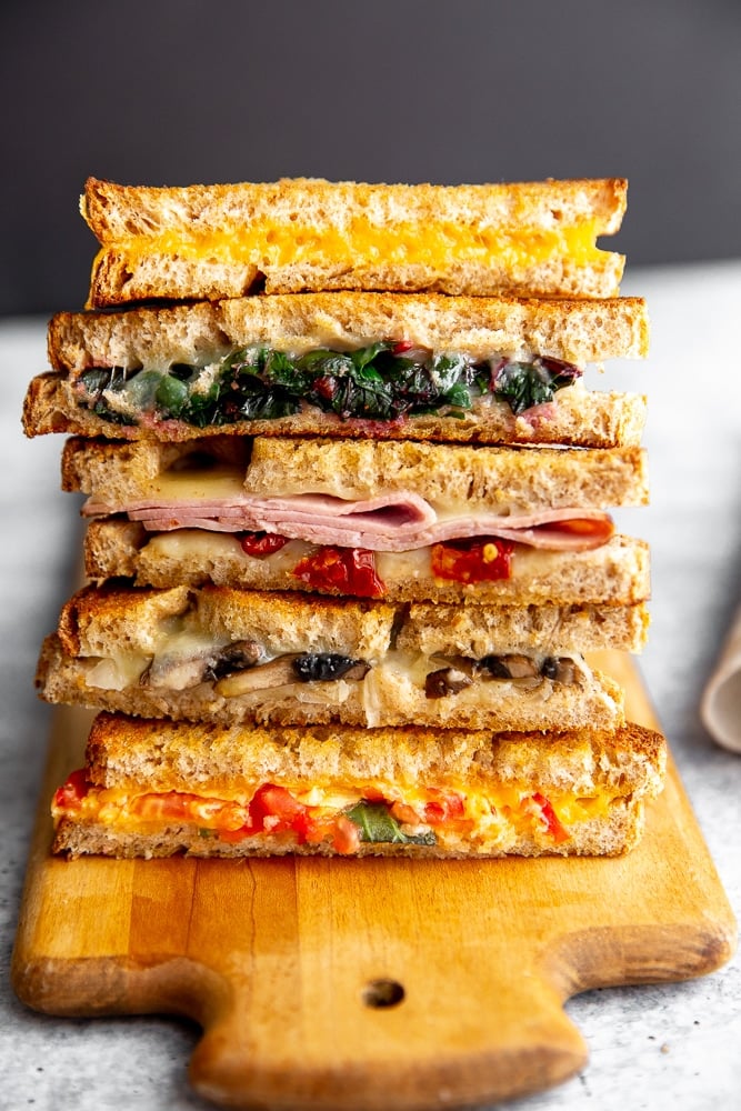 Grilled cheese sandwich halves stacked on a serving board. 