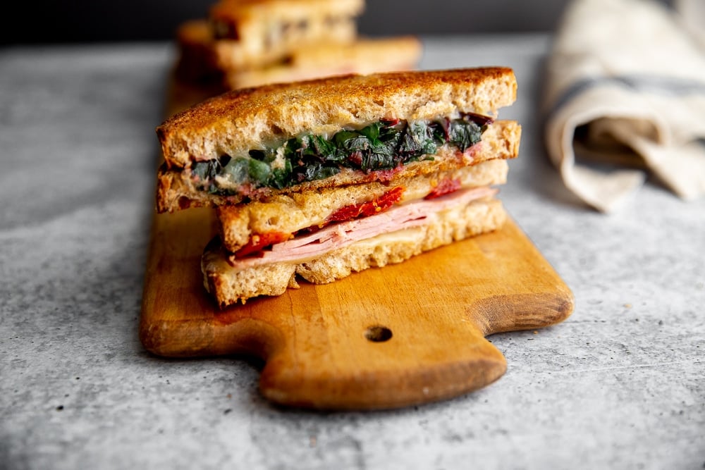 Two grilled cheese sandwhich halves, stacked on a serving board.