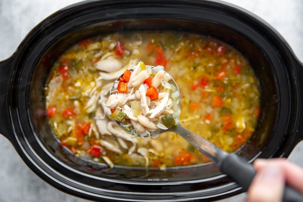 Overhead shot of a ladle scooping soup out of a slow cooker.