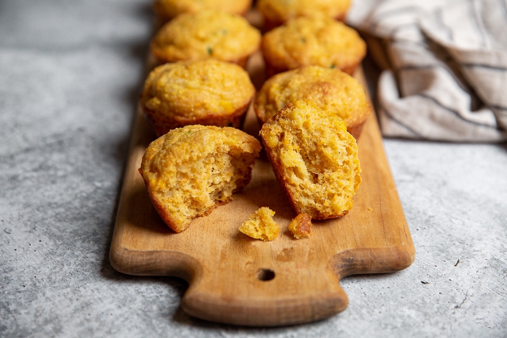 Cornbread muffins lined up on a serving board. 