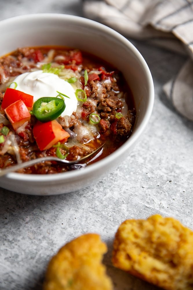 Close-up side view of a bowl of chili with a spoon.