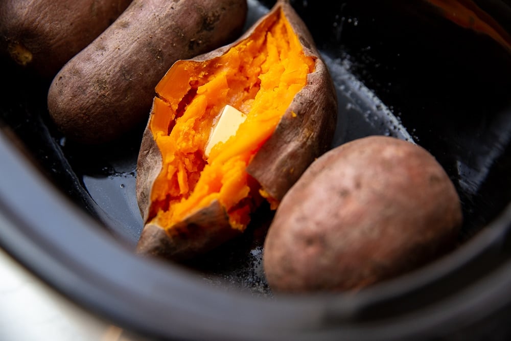 Close up of a buttered sweet potato in a slow cooker.