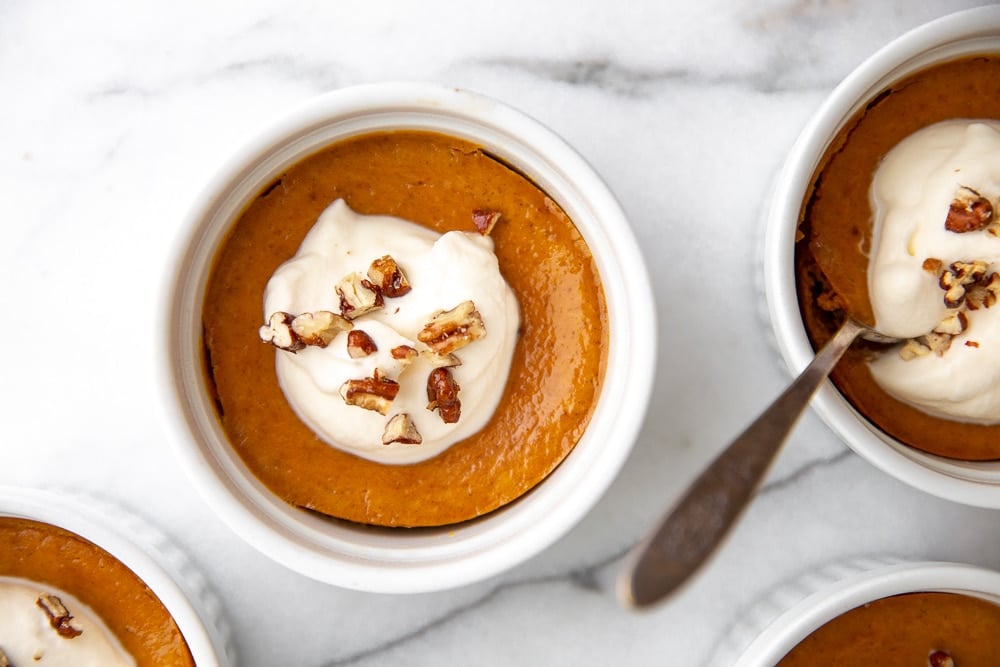 Individual crustless pumpkin pies on a marble surface.