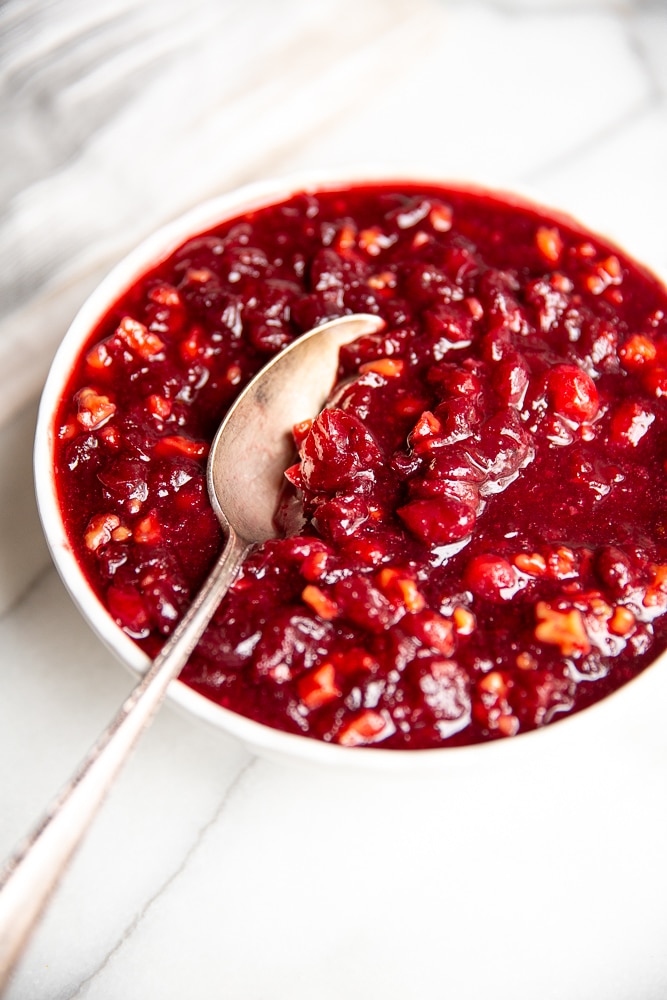 Close up of a bowl of cranberry sauce with a spoon.