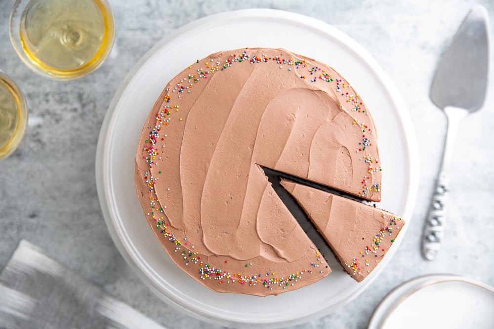 Chocolate quinoa cake with cocoa whipped cream frosting on a cake plate. 