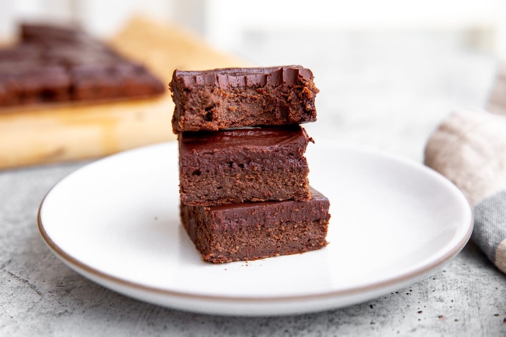 Three black bean brownies stacked on a plate.  