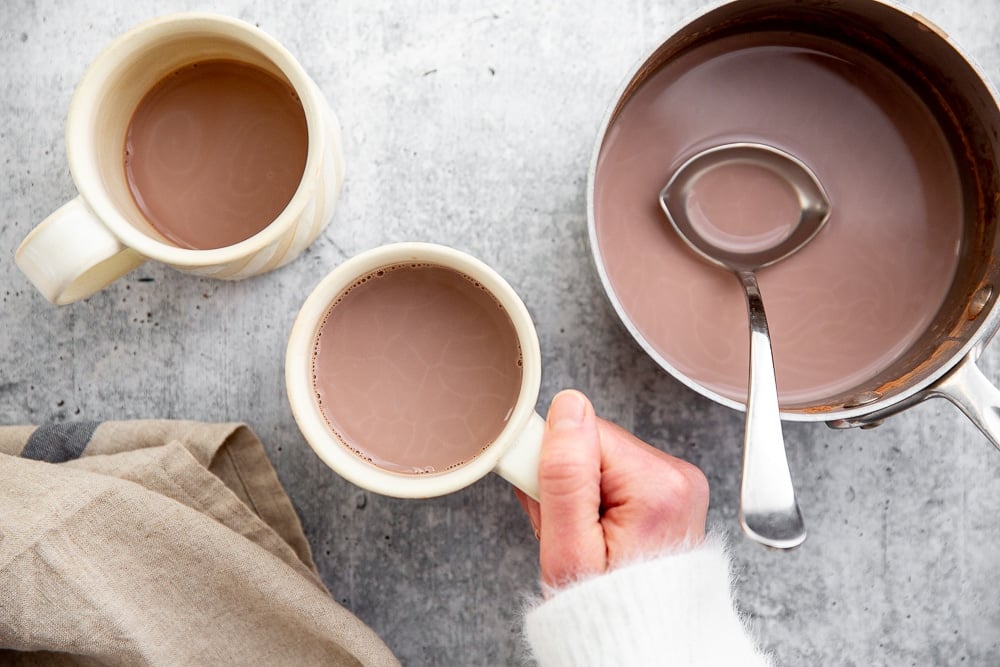 Hand holding a mug of vegan hot chocolate. 