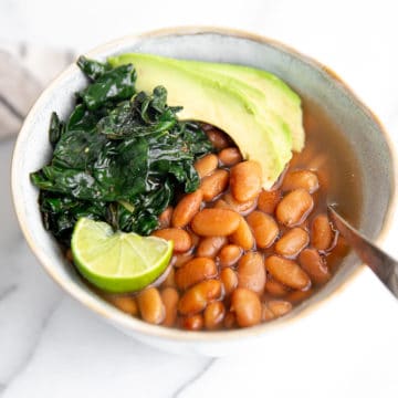 Bowl of instant pot pinto beans with kale and avocado.