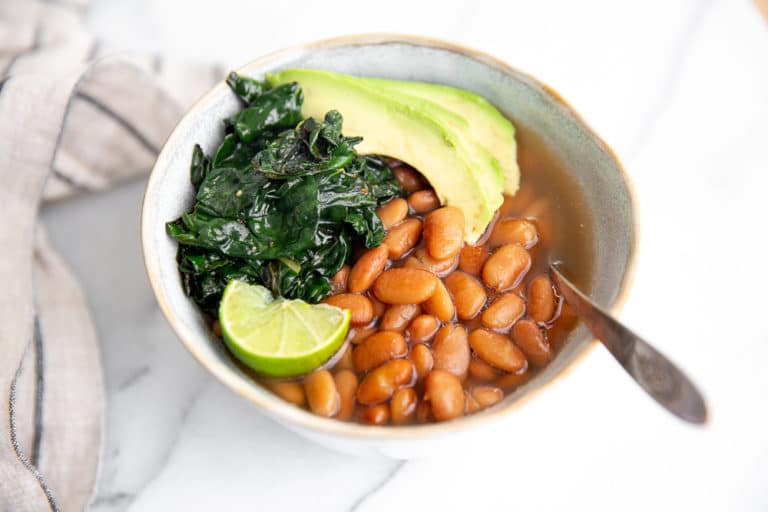 Bowl of instant pot pinto beans with kale and avocado.