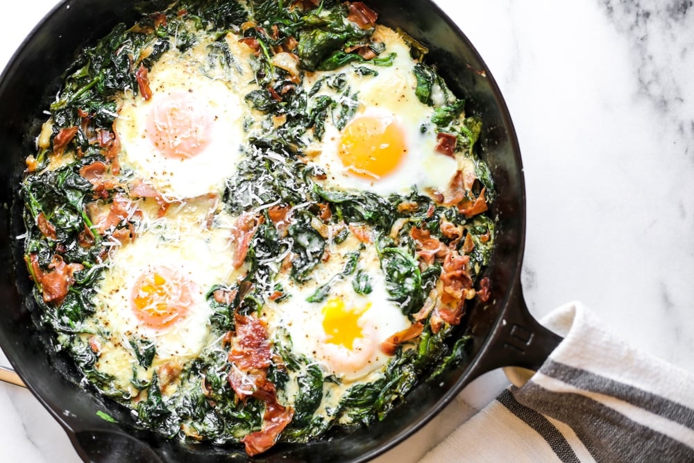 Overhead shot of spinach baked eggs in a cast iron skillet. 