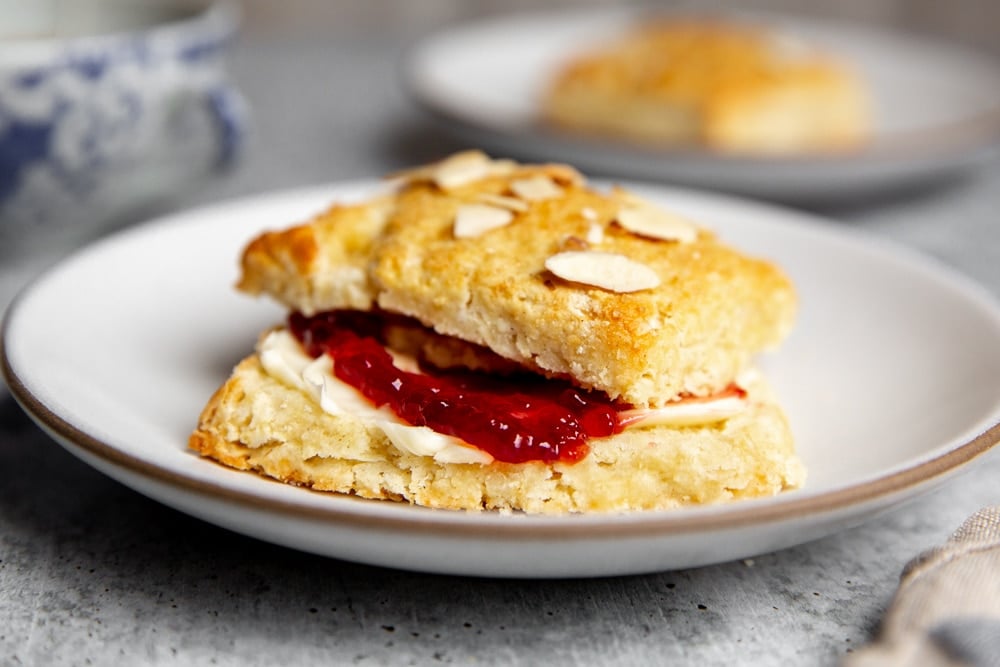 An almond shortcake on a plate filled with butter and jam. 