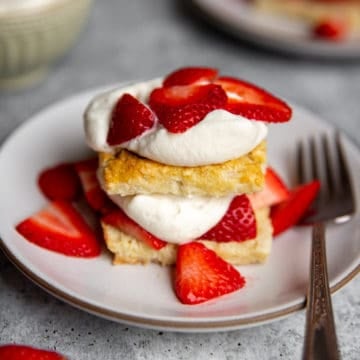 A strawberry shortcake on a plate topped with whipped cream and berries.