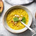 Slow cooker dal in a bowl, topped with herbs and chopped cashews.