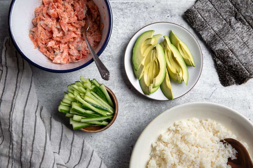 recipe ingredients for spicy salmon rolls on a counter. 