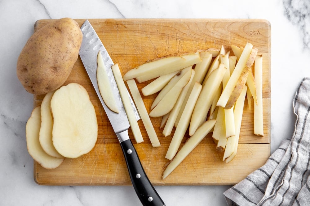 Process shot showing how to cut potatoes into french fries. 