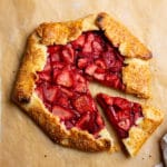 Strawberry galette on a piece of parchment paper with a slice pulled out.