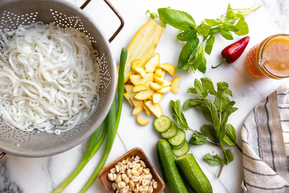 The ingredients for the rice noodle salad arranged on a marble countertop. 