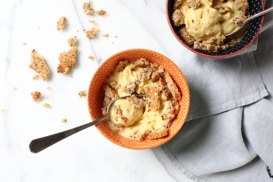 Two bowls of vegan mango ice cream topped with coconut peanut crumble.  