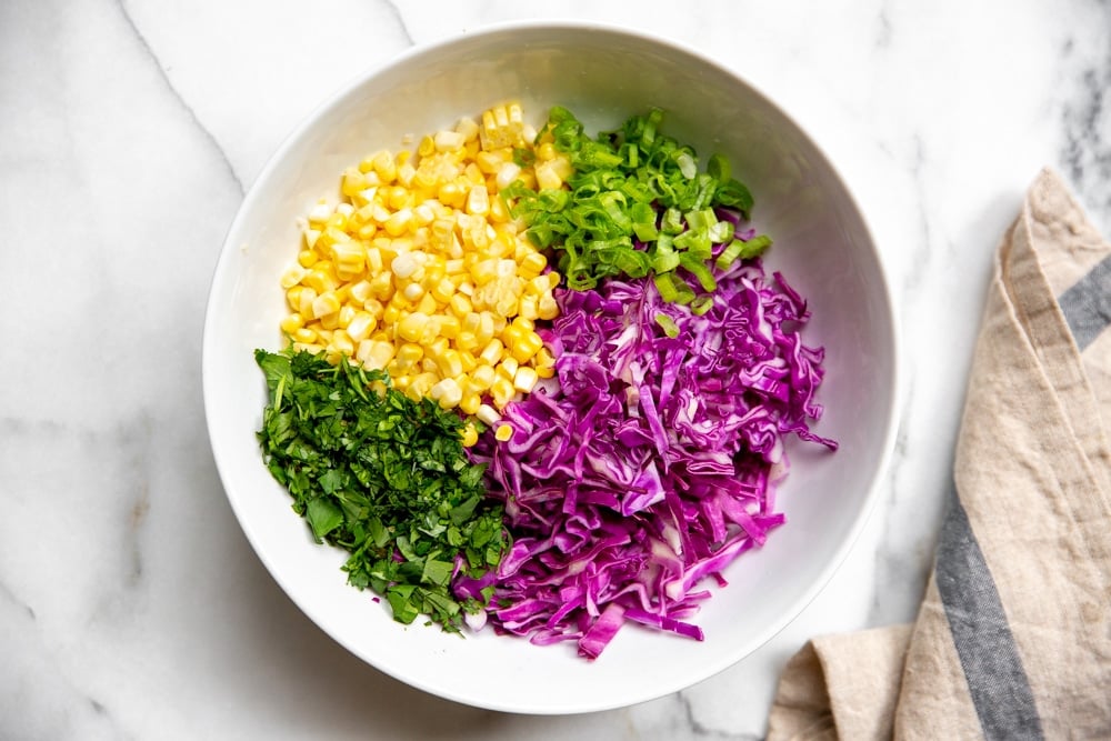 All of the ingredients for the red cabbage slaw arranged in a large bowl. 