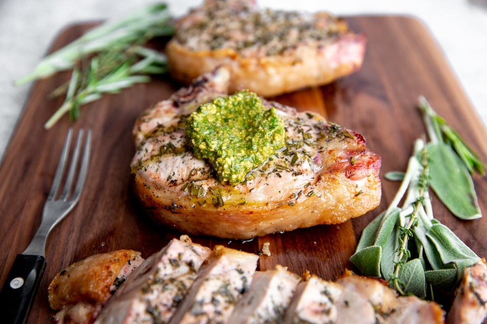 Close up of a grilled pork chop on a serving board. 