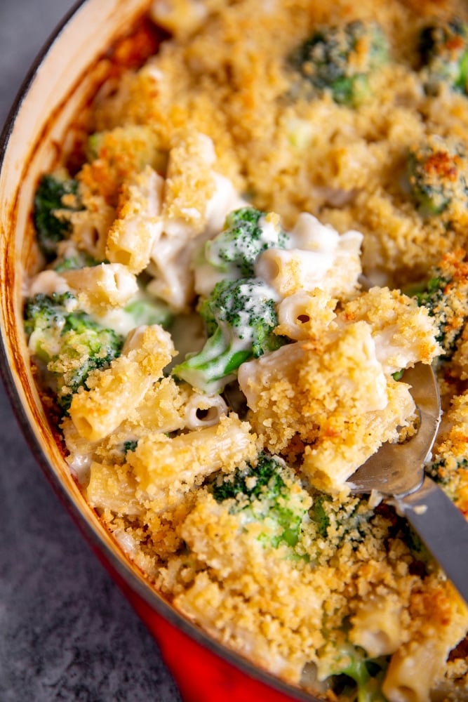 Close up of spoon scooping baked pasta with broccoli. 