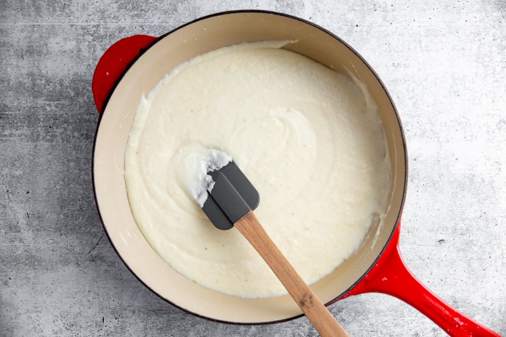 Creamy white sauce in a large skillet with a spatula. 