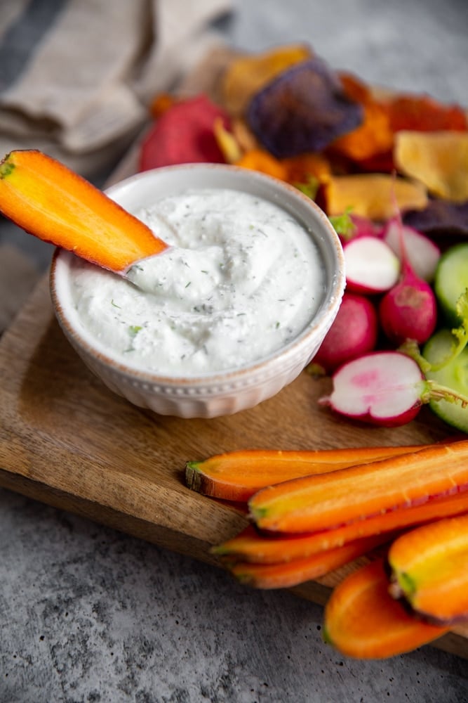 Close up of a carrot dipping into the cottage cheese dip. 