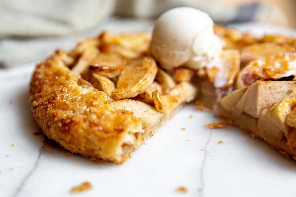 Close up of a sliced galette topped with vanilla ice cream. 