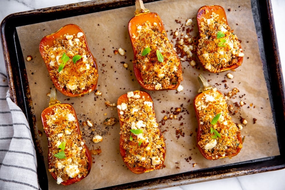 Baked lamb stuffed squash on a parchment lined baking sheet. 