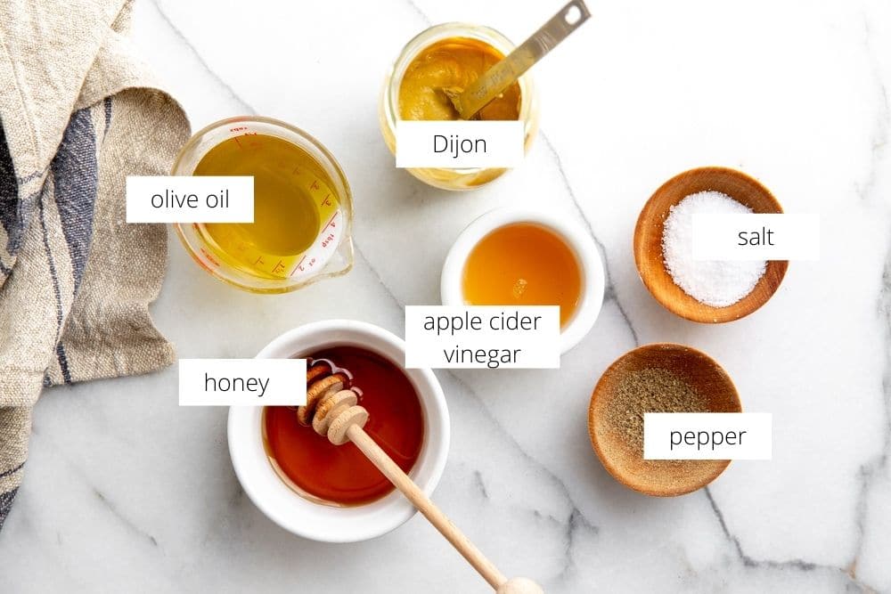 All of the apple cider vinaigrette ingredients arranged on a marble surface.