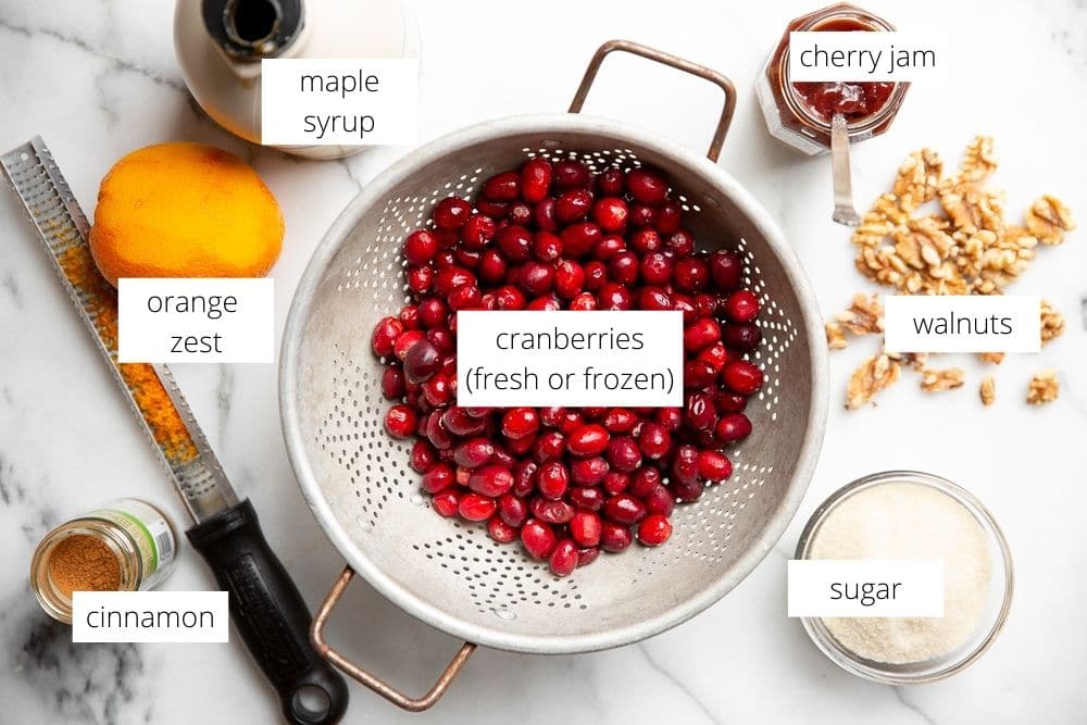 All of the ingredients for the easy cranberry sauce recipe arranged on a marble surface.