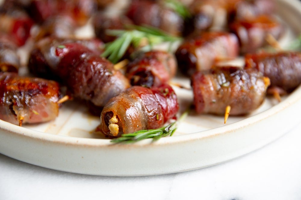 Close up of bacon wrapped dates on a serving platter.